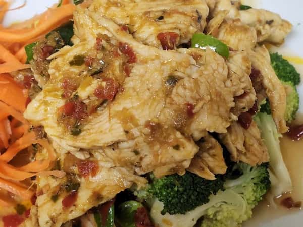 Close-up of shredded chicken stir-fry topped with a savory garlic and chili sauce, served over steamed broccoli and garnished with julienned carrots—ideal for a healthy and flavorful entrée.