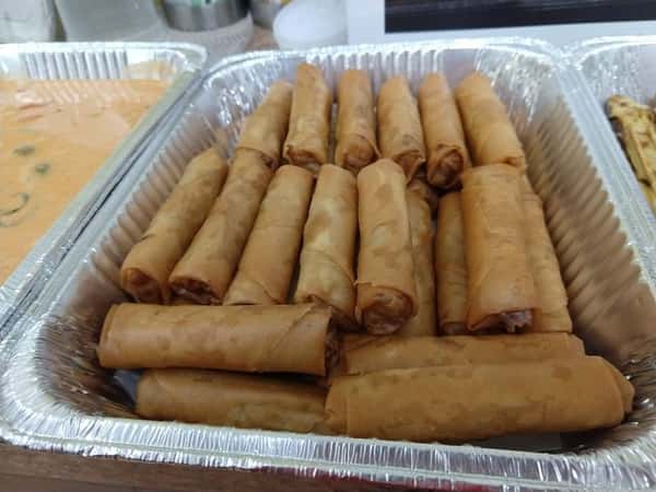 Golden-brown spring rolls neatly arranged in a foil tray, ideal for catering or appetizer platters at Asian restaurants.