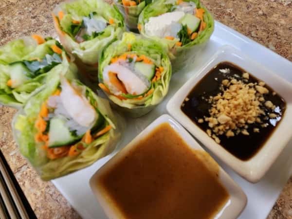 Fresh Thai spring rolls filled with shrimp, lettuce, cucumber, carrots, and rice noodles, served with peanut sauce and sweet hoisin dipping sauce topped with crushed peanuts.