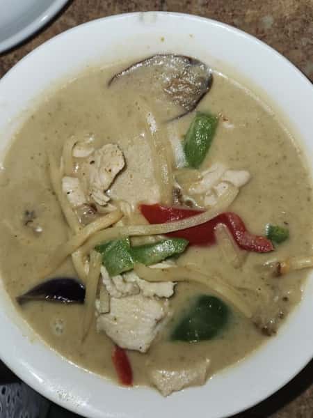 Bowl of creamy Thai green curry with chicken, bamboo shoots, bell peppers, and eggplant in a coconut milk-based green curry sauce—spicy, aromatic, and rich in flavor.