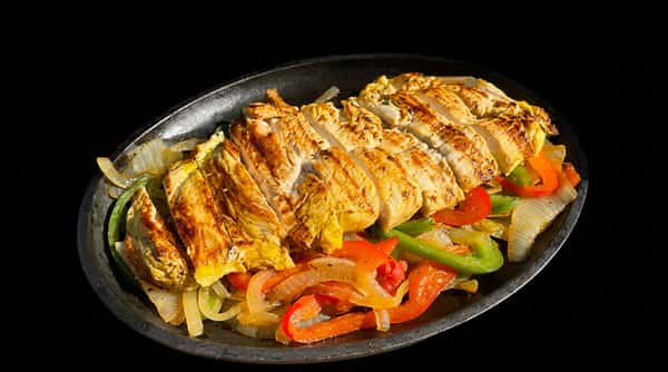 Chicken fajitas with sliced chicken breast, sautéed green, red, and orange bell peppers, and onions, on a dark platter.