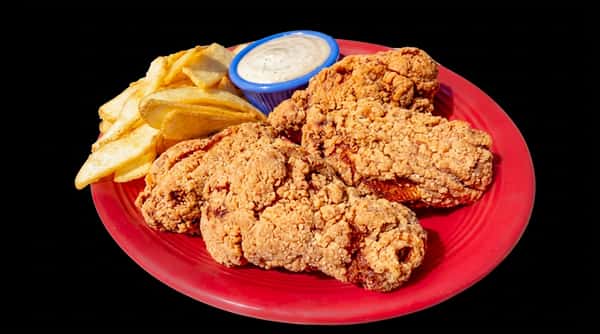 Fried chicken and potato wedges on a red plate with a side of white dipping sauce.