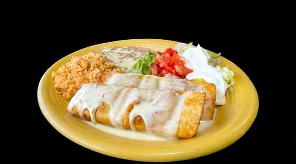 Two golden-brown chimi changas covered in white sauce, served with rice, refried beans, guacamole, and diced tomatoes on a yellow plate.