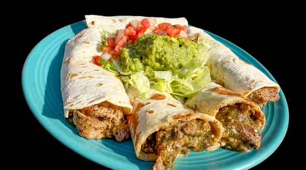 Four meat burritos on a blue plate with a side of guacamole, diced tomatoes, onions, and shredded lettuce.