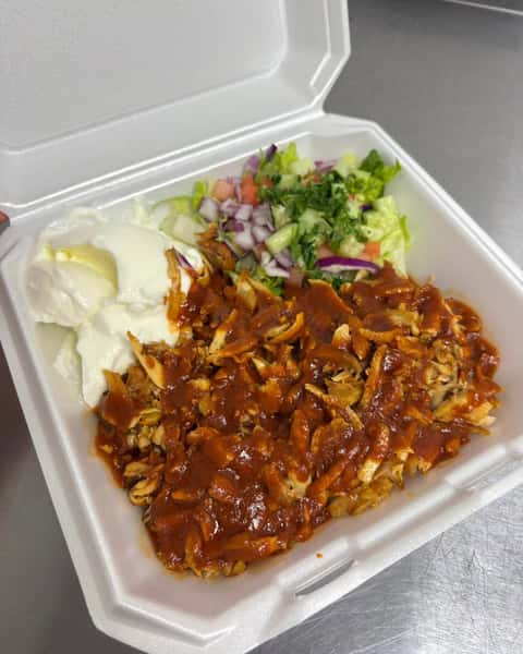 Chicken döner rice bowl topped with rich Turkish sauce, fresh salad, and creamy yogurt served in a takeout container