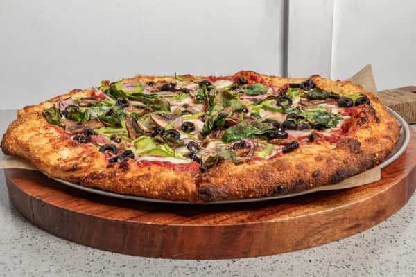 Crispy hand-tossed vegetarian pizza topped with spinach, black olives, red onions, green peppers, and mushrooms on a golden-brown crust.