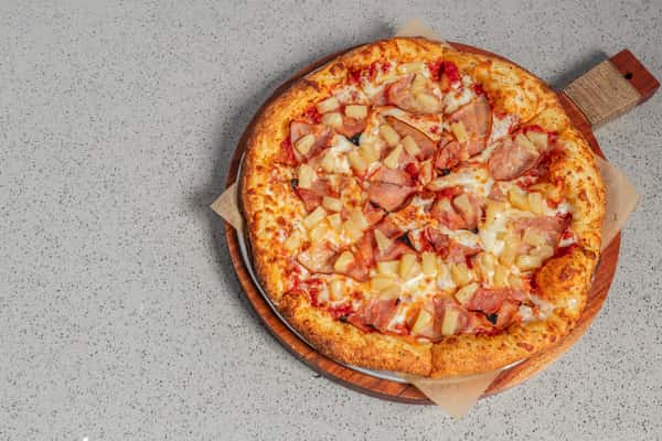 Whole Hawaiian pizza topped with savory ham and sweet pineapple chunks on a golden crust with melted mozzarella.