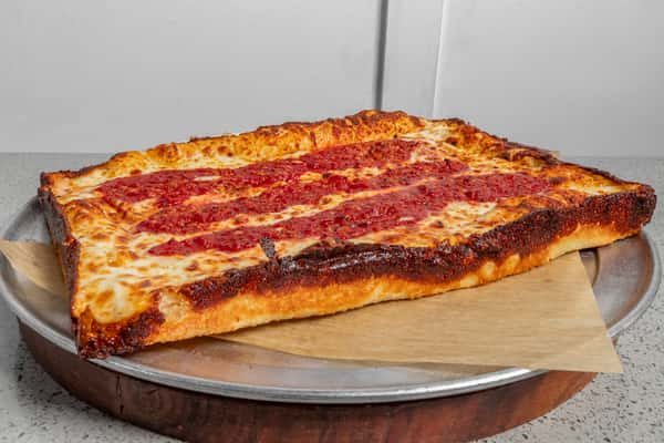 Thick-cut Detroit-style cheese pizza with a caramelized crust and signature tomato sauce stripes, served on a metal tray