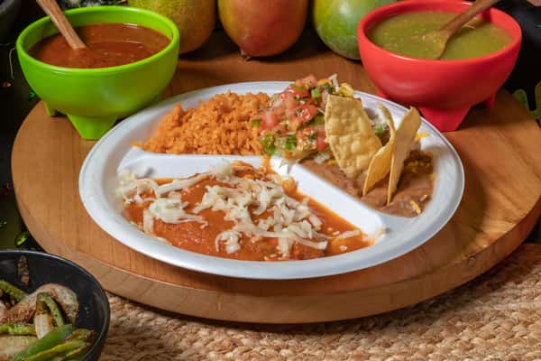 Classic Mexican combination plate featuring a cheese enchilada smothered in red sauce, served with Mexican rice, refried beans topped with tortilla chips, and a fresh pico de gallo salad. Surrounded by vibrant red and green salsas, highlighting traditional and comforting taqueria flavors.