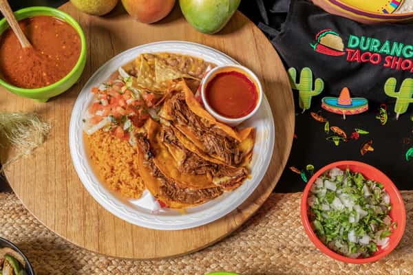 Authentic birria taco platter featuring cheesy beef birria tacos served with red consommé, Mexican rice, refried beans, pico de gallo, and tortilla chips.