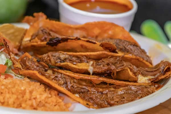 Close-up of cheesy beef birria tacos with crispy tortillas, slow-cooked shredded meat, and a side of rich consommé, served with rice and pico de gallo.