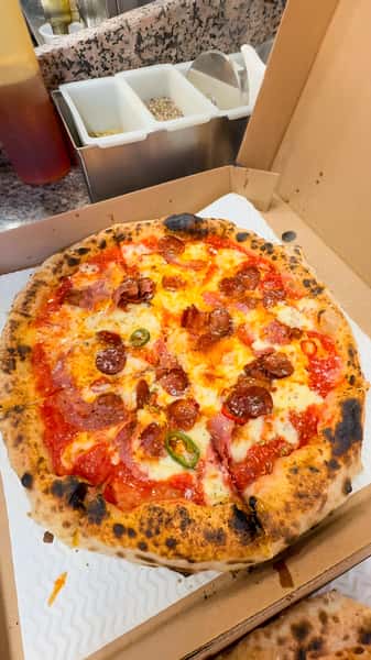 Pepperoni and chili pizza with red sauce and mozzarella cheese in an open pizza box.