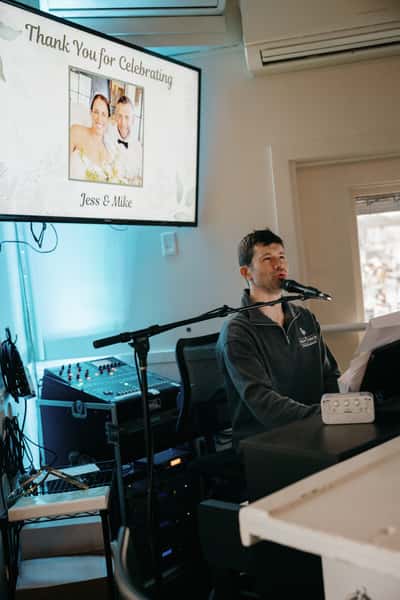 Pianist singing into a microphone beside a screen displaying "Thank You for Celebrating Jess & Mike" with their photo.