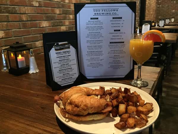 Egg, cheese and (bacon, smoked ham or corned beef hash) on a croissant with home fries, and a glass of orange juice in front of the manual menu