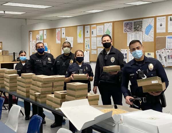 group of six police persons in front of a table full of Urth Lunch Boxes and coffee