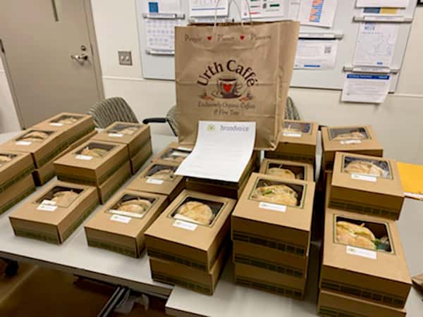 Table full of Urth lunch boxes with one big Urth bag sitting on top in the back.