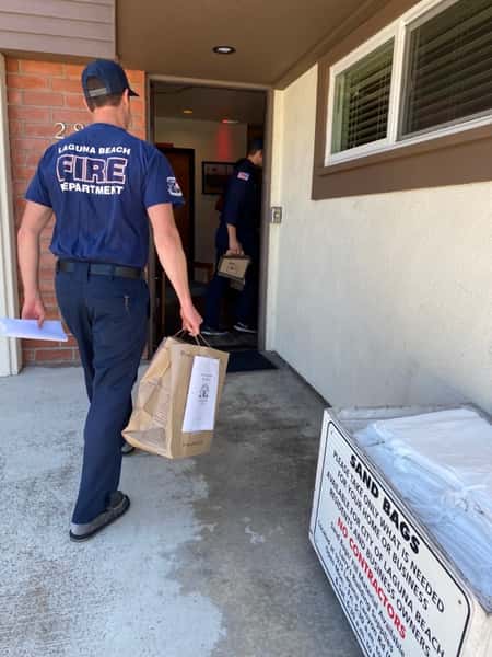 Laguna Beach fireman in t-shirt carrying Urth food bag into station