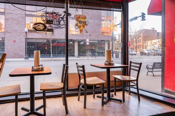 Interior of Si-Pie Pizzeria dining area with tables and floor-to-ceiling windows near Lakeview Chicago