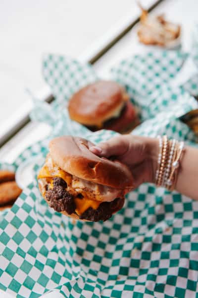 Close-up of a handcrafted cheeseburger with melted cheese and a toasted bun served at a beachside restaurant.
