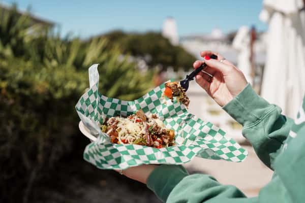 Outdoor seafood feast featuring fried shrimp, onion rings, sandwiches, sauces, and fresh sides at a coastal restaurant.