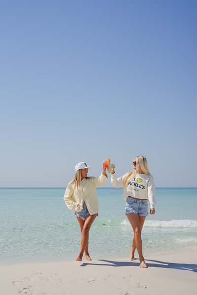 Two friends enjoying cocktails by the beach with ocean views, capturing a relaxed waterfront restaurant atmosphere.