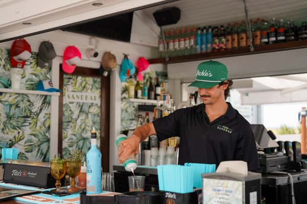Bartender preparing drinks behind a beach bar, showcasing handcrafted cocktails and waterfront hospitality.
