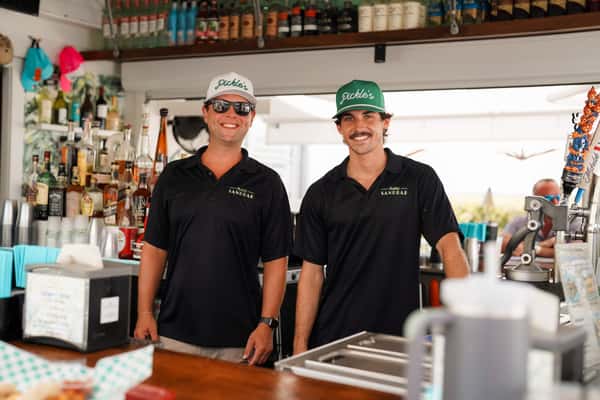 Restaurant staff members posing behind an outdoor bar, highlighting friendly hospitality and service.