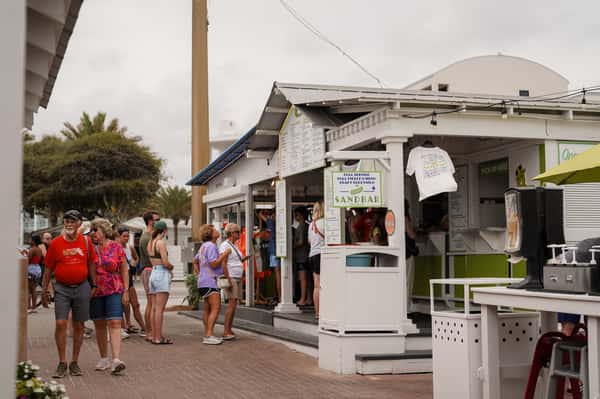 Guests gathered outside a popular beachfront restaurant ordering food and drinks at a coastal walk-up counter.