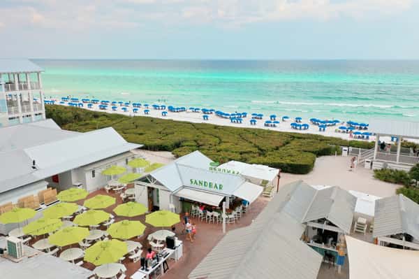 Aerial view of a beachfront restaurant with outdoor seating overlooking white sand beaches and turquoise water.
