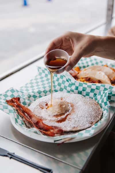 Freshly made funnel cake dusted with powdered sugar and topped with warm syrup at a seaside eatery.