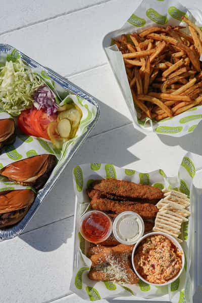 Restaurant spread featuring fresh seafood, sandwiches, salads, and fries arranged on an outdoor dining table.