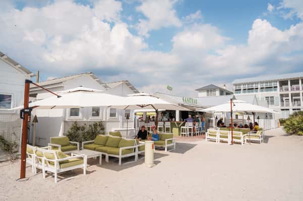 Spacious outdoor patio dining area with umbrellas and lounge seating at a waterfront restaurant.