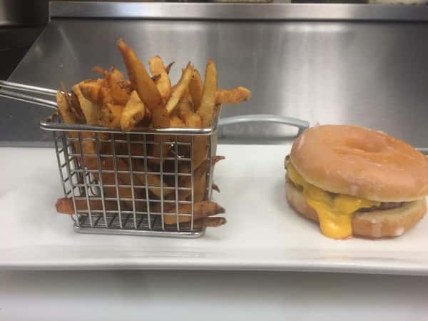 Cheese burger on a plate with a metal basket of fries