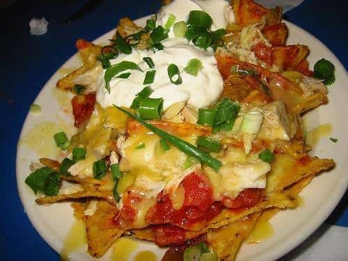 Loaded nachos on a plate with sour cream, chives, cheese and salsa