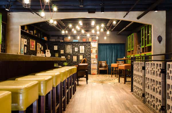 Cozy tequila library with bar seating and elegant green, wood, and black decor.