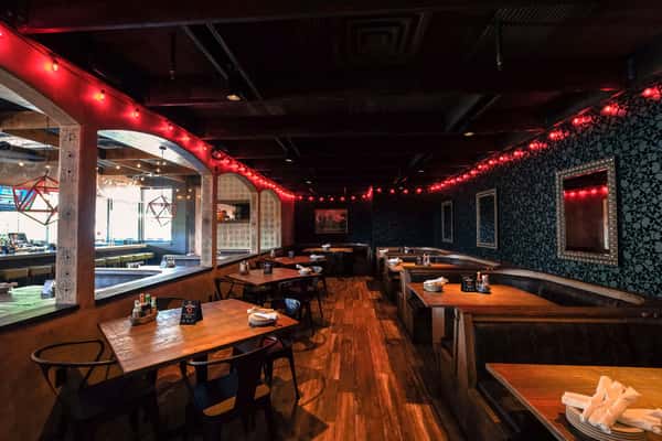 Large venue space for up to 350 people with booth and table seating, red string lighting and black grayscale skull wall paper pattern