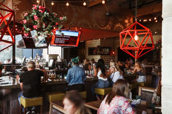 Interior dining with wood tables and bar with surrounding red decorative accents