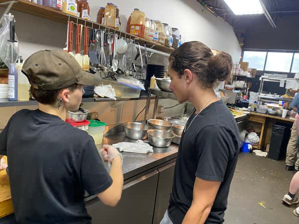 Restaurant kitchen staff preparing food at a stainless steel prep station, highlighting behind-the-scenes culinary teamwork.