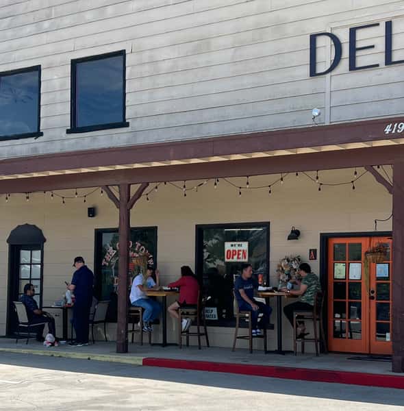 The exterior of The Old Town Deli, featuring outdoor seating where customers enjoy their meals.
