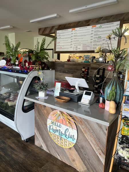 A cozy interior view of The Old Town Deli showcasing the counter with a menu board above, displaying options for cold and hot sandwiches.