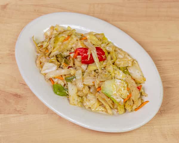 Seasoned sautéed cabbage mixed with bell peppers, carrots, and spices, served on a white plate—classic West African-style vegetable side dish.