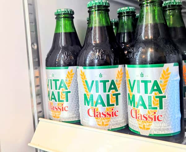 Chilled bottles of Vita Malt Classic non-alcoholic malt beverage, displayed in a refrigerator — popular West African and Caribbean soft drink known for its rich, malty flavor.