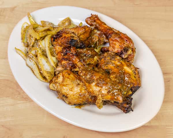 Plate of spicy grilled chicken coated in a flavorful herb marinade, served with sautéed onions, showcasing a popular West African-style roasted chicken dish.
