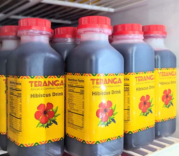 Row of Teranga-branded hibiscus drinks in plastic bottles with red caps and bright yellow labels, showcasing a popular West African and Caribbean beverage.