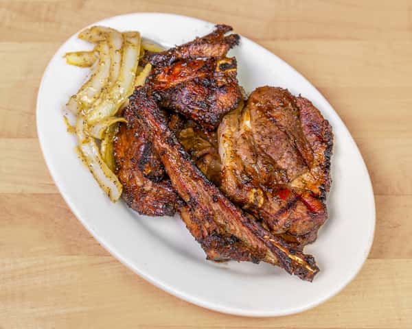 Plate of flame-grilled goat meat and ribs seasoned with West African spices, served with sautéed onions, highlighting a bold and smoky Nigerian-style barbecue dish.