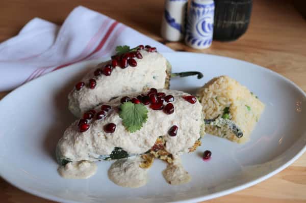 Crab-stuffed fish topped with creamy sauce and pomegranate garnish, served with rice and vegetables at Hugo's restaurant.