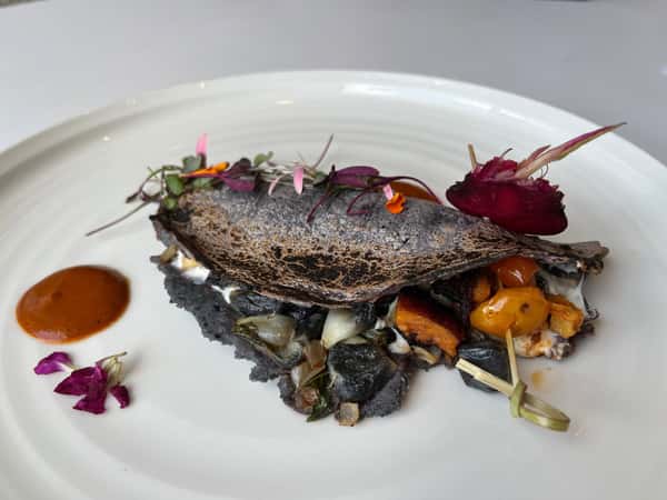 Blackened fish entrée with roasted vegetables and elegant plating, served at Hugo's restaurant for an upscale Southern coastal dining experience.