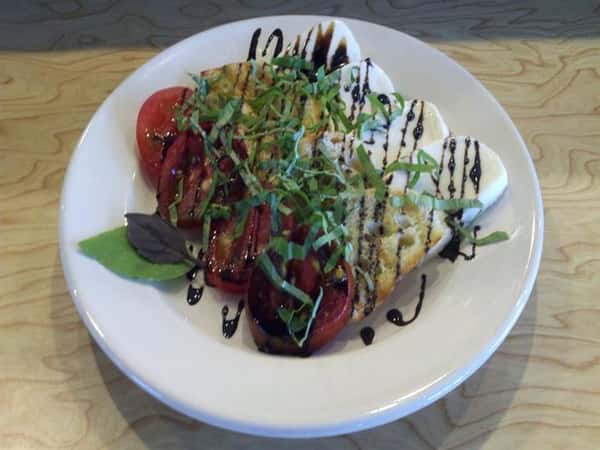 Chef specialty dish with tomatoes, cracker, and cheese drizzled in sauce