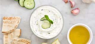 tzatziki sauce in a bowl with herbs and cucumber slice