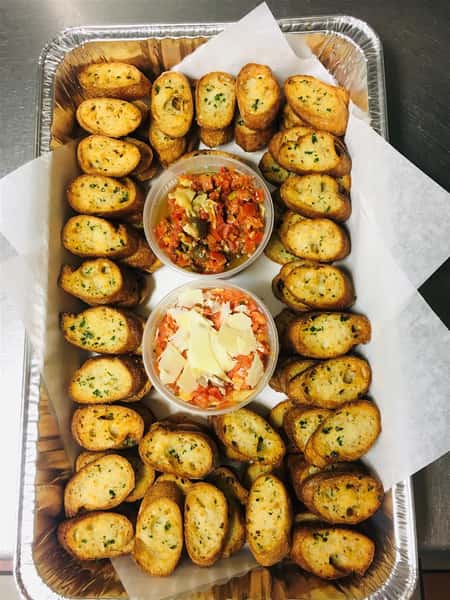 Toasted bread topped with oil, garlic, and cheese with two dips in a foil tray